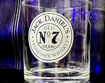 May include: A clear, tumbler-style whiskey glass featuring the Jack Daniel's Old No. 7 Brand logo. The logo is a circular design in black and white, with the words "Jack Daniel's" and "Tennessee Whiskey" around "Old No. 7 Brand".