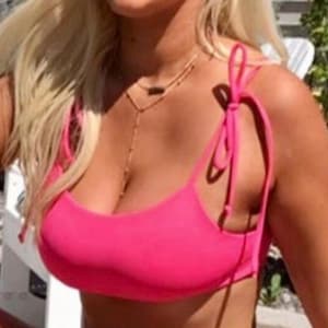 May include: A bright pink bikini top with tie straps. The top is a solid color and has a scoop neckline. A gold necklace is visible.