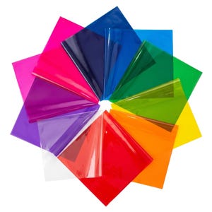 May include: A collection of colorful, transparent sheets arranged in a circular pattern. The sheets display a variety of vibrant colors, including pink, red, blue, green, and yellow. The arrangement creates a visually appealing display of color and light.