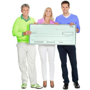 May include: Three people holding a large blank check. The check is light green with black text and a space for the dollar amount. The people are wearing casual clothing in shades of green, pink, and blue.