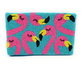 May include: A beaded clutch featuring a repeating pattern of pink flamingos with yellow beaks and black accents against a turquoise background. The flamingos have closed eyes, suggesting a relaxed theme.