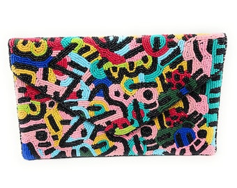 May include: A black beaded clutch with a colorful abstract design. The clutch is made of small beads in various colors, including pink, blue, green, yellow, and red.