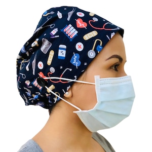 May include: A black scrub hat with a colorful medical print featuring stethoscopes, hearts, pills, bandages, and other medical symbols. The hat has a button on the side for adjusting the fit.
