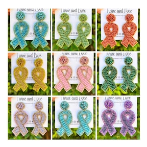 May include: Nine pairs of beaded ribbon earrings in various colors, including teal, green, pink, yellow, orange, purple, and blue. Each pair features a double-looped ribbon design.