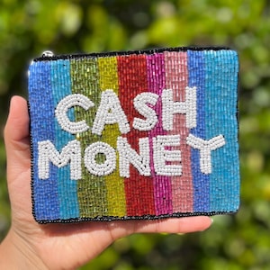 May include: A beaded clutch with the words "CASH MONEY" in white beads. The clutch features vertical stripes in shades of blue, green, yellow, red, and pink. The edges are outlined in black.
