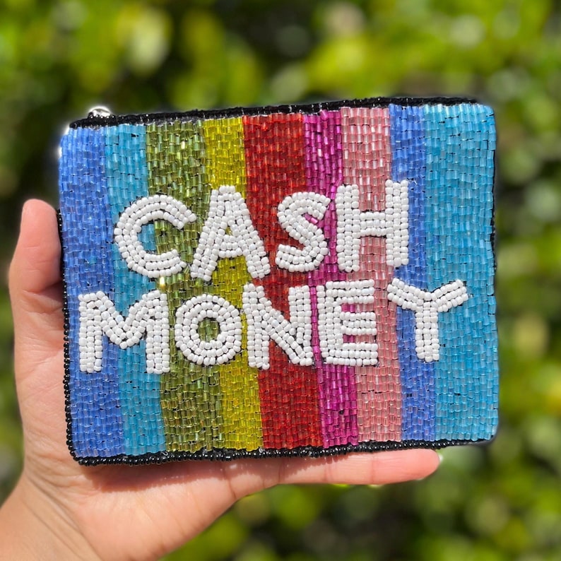 May include: A beaded clutch with the words "CASH MONEY" in white beads. The clutch features vertical stripes in shades of blue, green, yellow, red, and pink. The edges are outlined in black.