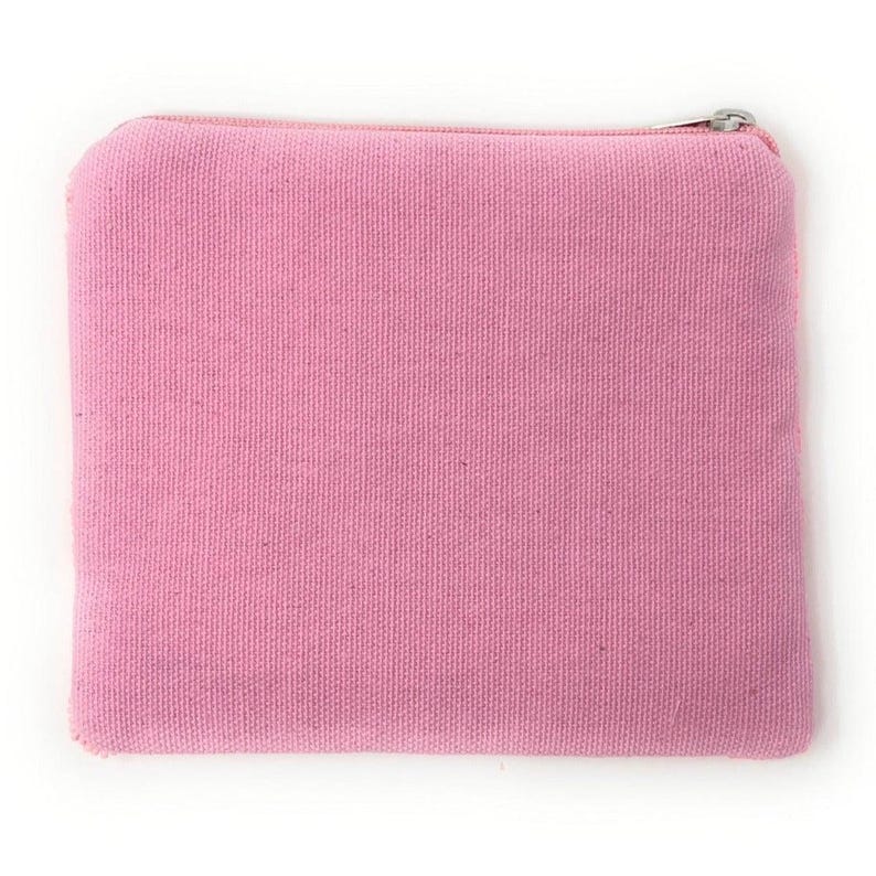 May include: A small, rectangular pink canvas pouch with a zipper closure. The pouch is a solid, light pink color and appears to be made of a textured fabric. The zipper is silver-colored.