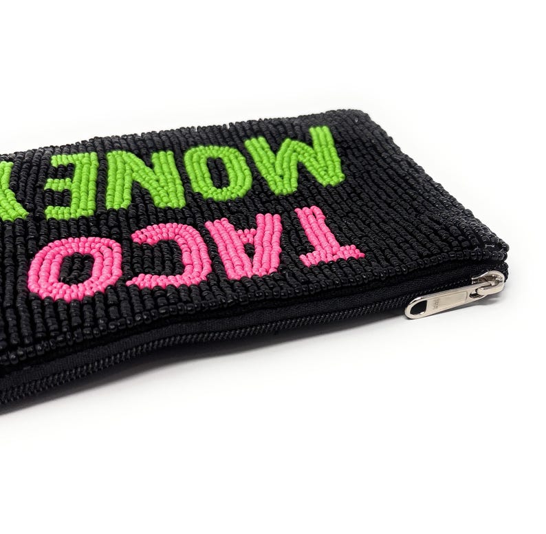 May include: Black beaded pouch with the words "TACO MONEY" in bright pink and green beads. The pouch has a black zipper and is likely used for carrying small items like cash or cards. The design is fun and playful.