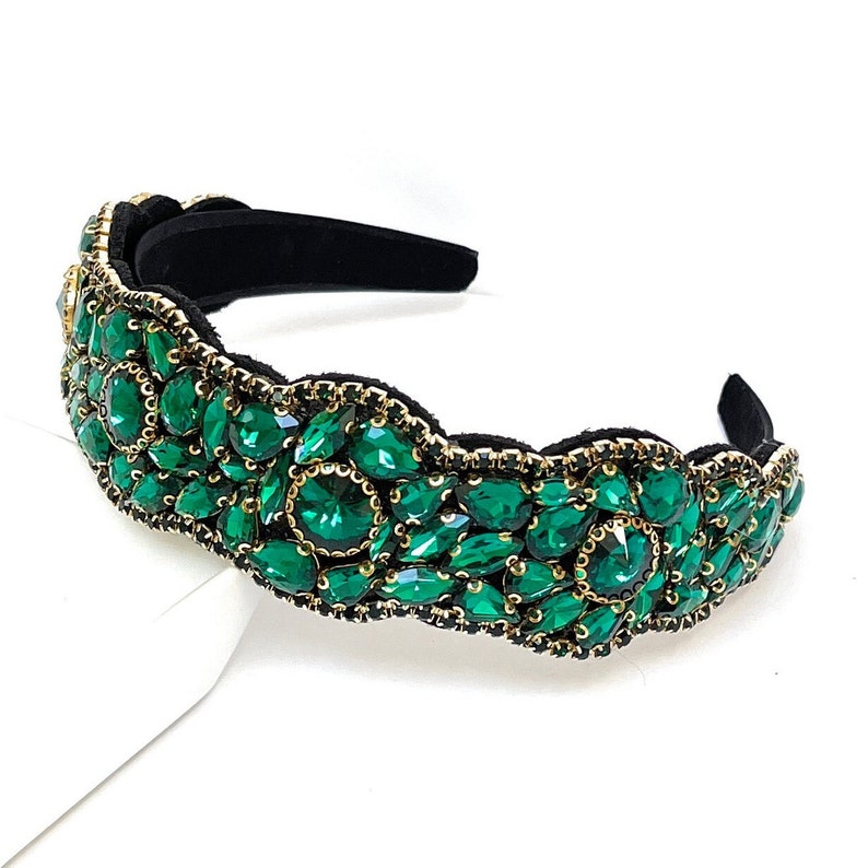 May include: A green jeweled headband with a black velvet band. The headband is decorated with emerald green rhinestones.