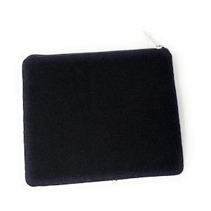 May include: A black rectangular pouch with a silver zipper. The pouch is made of a textured fabric and is set against a white background. The zipper is at the top of the pouch.