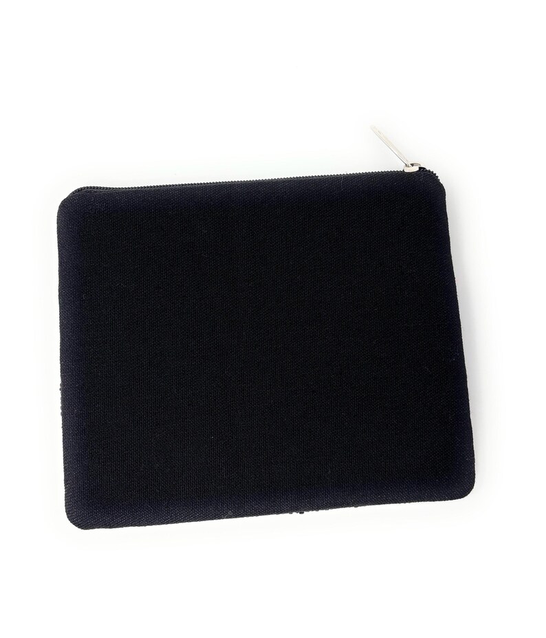 May include: A black rectangular pouch with a silver zipper. The pouch is made of a textured fabric and is set against a white background. The zipper is at the top of the pouch.