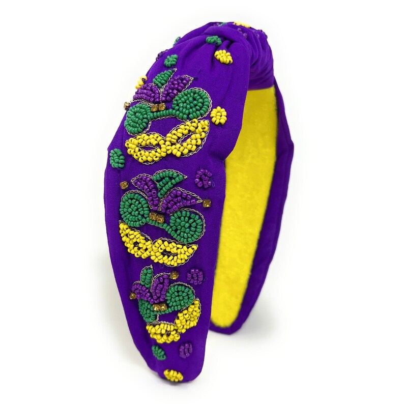 May include: Purple headband with a knotted design and beaded embellishments in green, yellow, and purple.