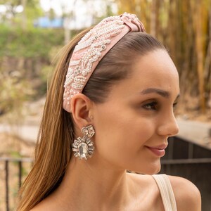 Close-up of a woman wearing a pink embellished headband and sparkling earrings.