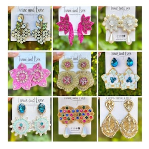 May include: A collection of handmade earrings in various designs. The earrings feature intricate beadwork, gemstones, and pearl accents. Styles include floral, teardrop, and chandelier designs, with colors like pink, gold, blue, and clear. The brand name "Twine and Love" is visible.
