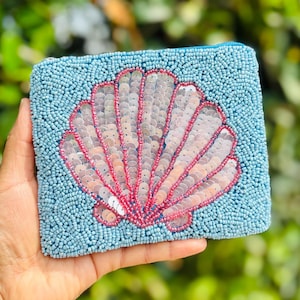 This beaded coin purse featuring charming seashell design is a must-have accessory. Its compact size allows for convenient storage while adding a delightful touch to any outfit. Adorned with shiny sequins, it is both fashionable and functional. A valuable addition to any fashion enthusiast's collection.