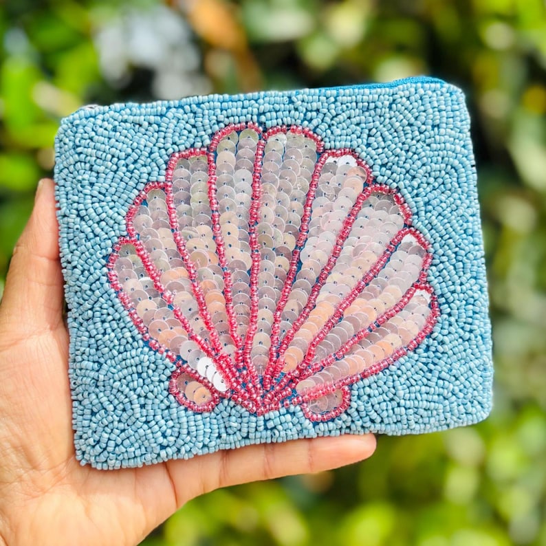 This beaded coin purse featuring charming seashell design is a must-have accessory. Its compact size allows for convenient storage while adding a delightful touch to any outfit. Adorned with shiny sequins, it is both fashionable and functional. A valuable addition to any fashion enthusiast's collection.