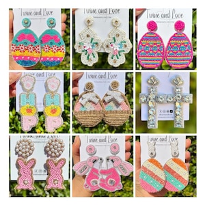 May include: Nine pairs of colorful beaded earrings with Easter themes. The earrings feature designs such as eggs, bunnies, baskets, and crosses. The earrings are all handmade and have a whimsical and festive feel.