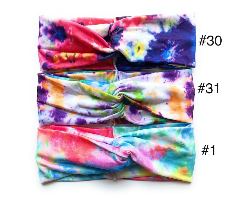 May include: Three tie-dye headbands in different colour combinations. The top headband is pink, purple, and yellow. The middle headband is white, purple, yellow, and green. The bottom headband is pink, blue, and yellow. The headbands are labelled #30, #31, and #1.