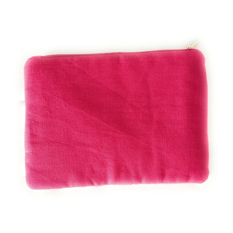 May include: A bright pink zippered pouch made of a soft, textured fabric. The pouch is ideal for storing small items like makeup, jewelry, or electronics.