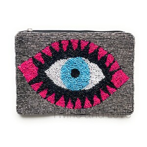 May include: A beaded clutch bag with a large, colorful evil eye design. The eye is blue, white, and black with pink accents. The bag is made of silver beads.