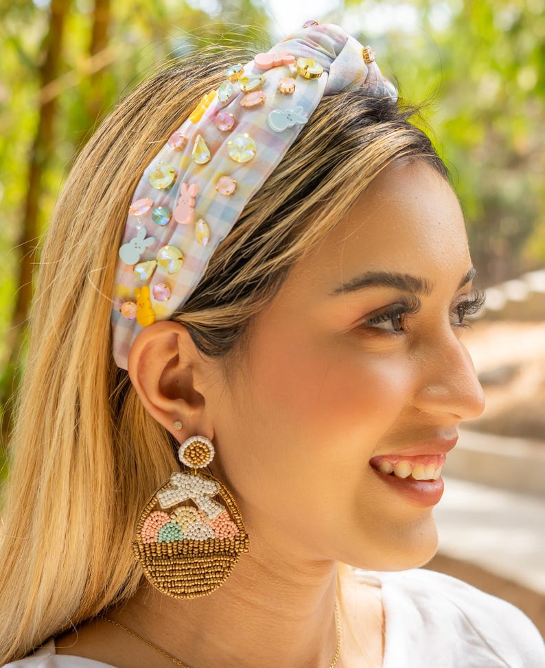Enhance your spring look with our beautiful Peeps Easter Jeweled Knotted Headband. Handmade with pastel color gingham fabric and delicate pastel color jewels, this headband is adorned with adorable peeps bunny charms. Elevate your style with this exclusive and elegant accessory.