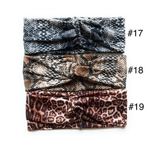 May include: Three fabric headbands with different animal print patterns. The top headband is a black and white snake skin pattern, the middle headband is a brown and black snake skin pattern, and the bottom headband is a brown and black leopard print pattern. The headbands are labelled #17, #18, and #19.