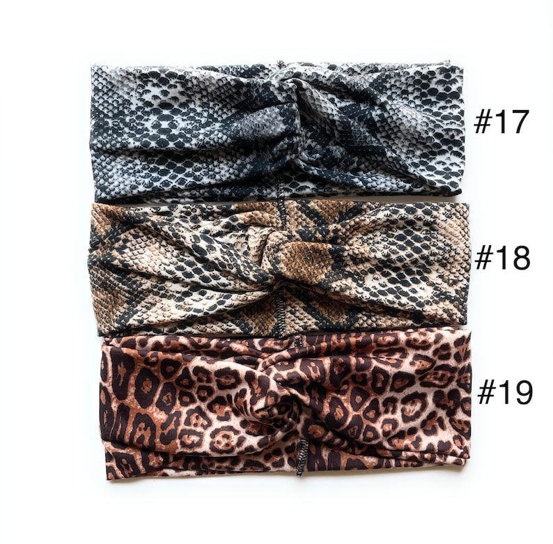 May include: Three fabric headbands with different animal print patterns. The top headband is a black and white snake skin pattern, the middle headband is a brown and black snake skin pattern, and the bottom headband is a brown and black leopard print pattern. The headbands are labelled #17, #18, and #19.