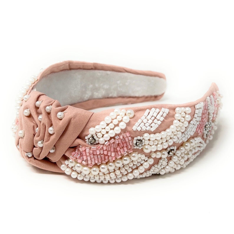 May include: A pink knotted headband with white and pink beads and pearls.
