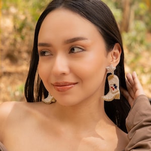 Close-up of a woman wearing stylish boot-shaped earrings with a star accent.