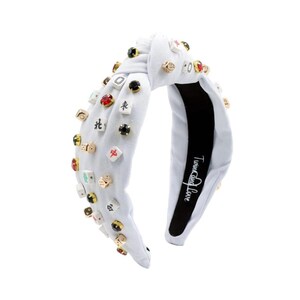 A white headband with a twisted design, adorned with various colorful gemstone studs and Mahjong tile charms, conveying a playful and eclectic style.