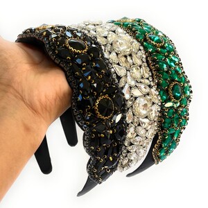 May include: Three black, white, and green headbands with jeweled embellishments. The headbands are made of a black elastic material and are decorated with rhinestones, faux pearls, and other jewels.