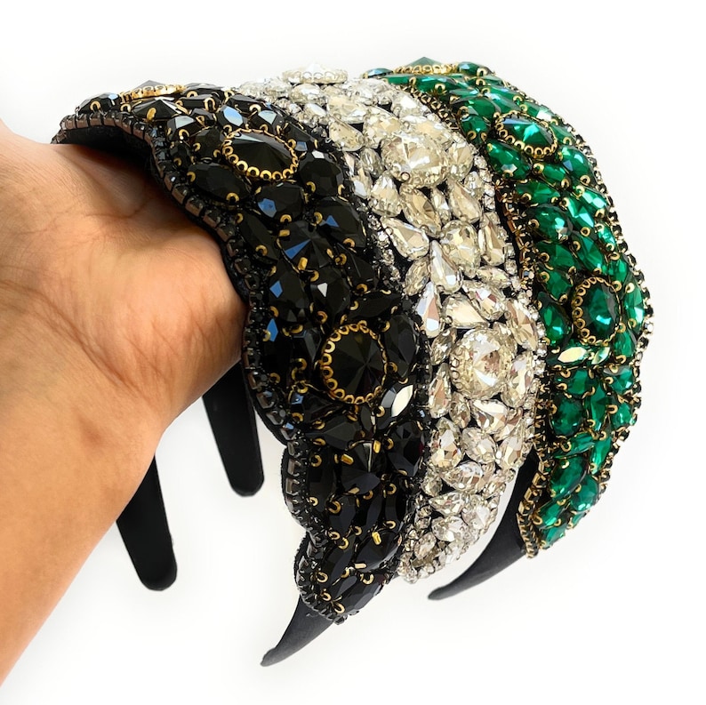 May include: Three black, white, and green headbands with jeweled embellishments. The headbands are made of a black elastic material and are decorated with rhinestones, faux pearls, and other jewels.
