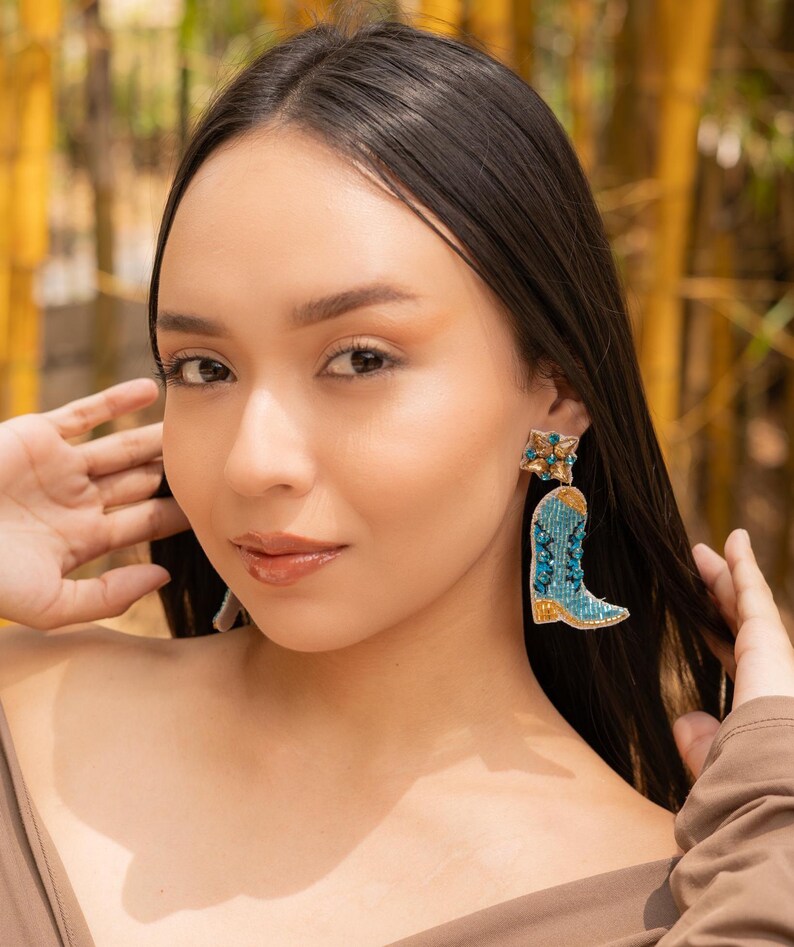 model showcasing colorful boot-shaped earrings in a natural setting.