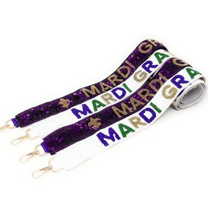 May include: Three Mardi Gras themed straps with gold, green, purple, and white beaded text and accents. The straps have silver clasps and are made of sequins. The text reads "MARDI GRAS".