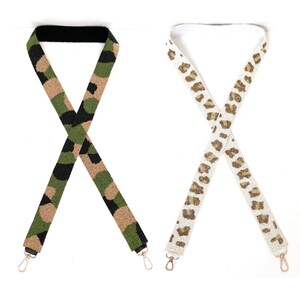 Pu&ograve; includere: Due cinturini per borsa in perline, uno con un motivo mimetico in verde, nero e marrone, e l'altro con una stampa leopardata bianca e oro.