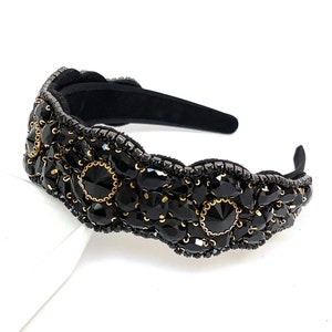 May include: Black headband with a decorative design of black and gold rhinestones.