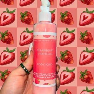 May include: A pink body lotion bottle with a white pump, labeled "Strawberry Shortcake Body Icing." The bottle is held against a pink and red strawberry pattern background. The label includes the brand name "Endless Glow Skincare."