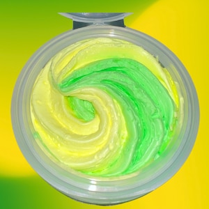 May include: A small clear container with a swirl of yellow and green whipped body butter.
