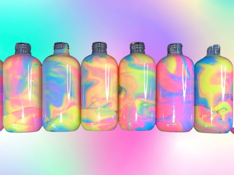 May include: A row of clear glass bottles filled with colorful, swirled liquid. The liquid features a mix of pink, yellow, blue, and purple hues. The bottles have silver-colored necks and are arranged against a gradient background.
