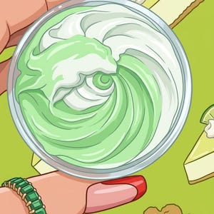 May include: A clear glass bowl filled with green and white swirled cream. The cream has a smooth texture and is surrounded by a light green background with lime and pie slice illustrations. A hand with a green bracelet and red nail polish holds the bowl.