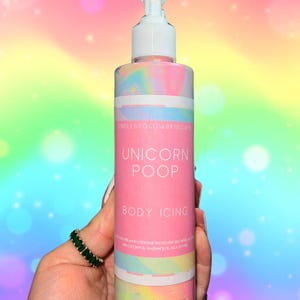 May include: A pink and white body icing bottle with a white pump dispenser. The label reads "Unicorn Poop Body Icing" with the Endless Glow Skincare logo. The background is a rainbow gradient.