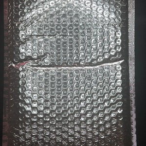 May include: A silver bubble wrap envelope with a textured surface. The envelope is sealed on three sides.