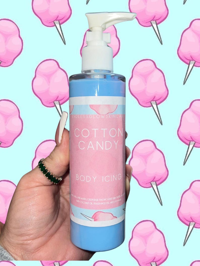 May include: A blue and pink bottle of "Cotton Candy Body Icing" with a white pump top. The label is pink with white text. The background is a light blue color with a pattern of pink cotton candy.
