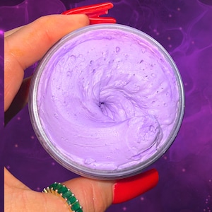 Może przedstawiać: Mały słoiczek lawendowego, ubijanego masła do ciała. Masło jest spiralnie ułożone i ma gładką, kremową konsystencję.