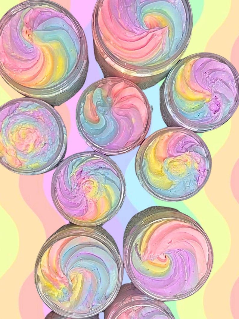 K&ouml;nnte beinhalten: Mehrere Beh&auml;lter mit buntem, geschlagenem K&ouml;rperbutter mit Wirbeln in Rosa, Gelb, Blau und Lila.