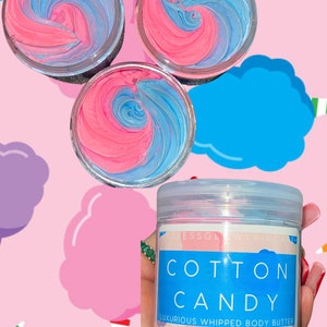 K&ouml;nnte beinhalten: Drei Gl&auml;ser mit rosa und blauem geschlagenem K&ouml;rperbutter, beschriftet mit "Cotton Candy" und "Luxurious Whipped Body Butter". Die Gl&auml;ser befinden sich auf einem rosa Hintergrund mit Wattebausch-Wolken.