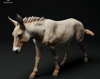 May include: A detailed miniature donkey figurine, in cream and tan hues. The model has a textured coat and is posed walking. The text "ANIMAL DEN MINIATURES" is visible in the upper left corner.