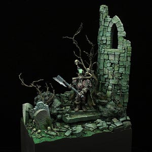 May include: A miniature figure of a warrior with a large axe, wearing red armor and a green cloak, standing on a stone platform in a ruined building. The scene is set in a graveyard with a tombstone and skeletal remains.