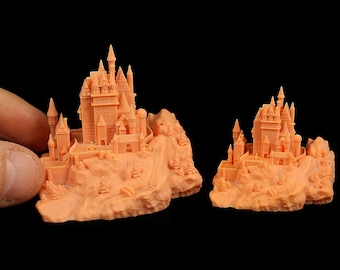 May include: Two 3D printed miniature castles on a rocky base, one larger than the other, both in a light orange color.