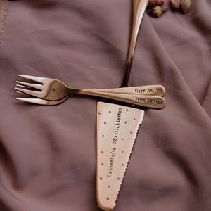 Könnte beinhalten: Ein Set aus drei Keramikbechern mit gesprenkelter, matter Oberfläche. Die Becher sind in Creme-, Hellgrau- und Dunkelgrautönen gehalten. Jeder Becher hat ein schlichtes, minimalistisches Design.